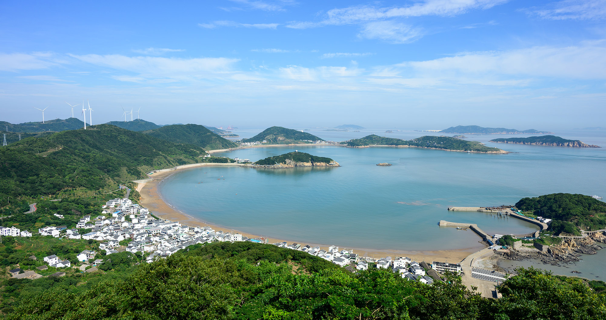 衢山岛海湾全景，远处可见风力发电机与白色村落
