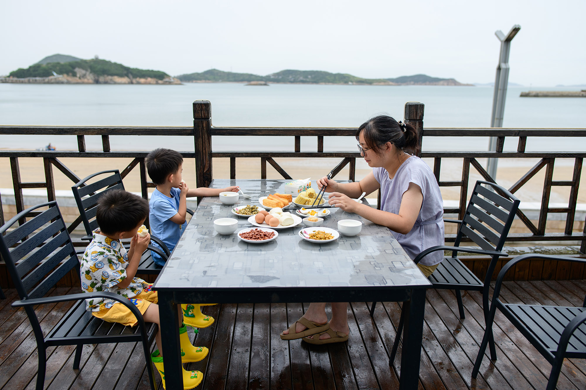 一家三口在海边露台餐厅享用早餐，海景相伴
